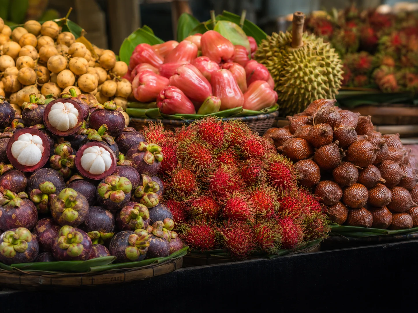 A colorful Thai market display of mangosteen, rambutan, rose apple, langsat, salak, and durian